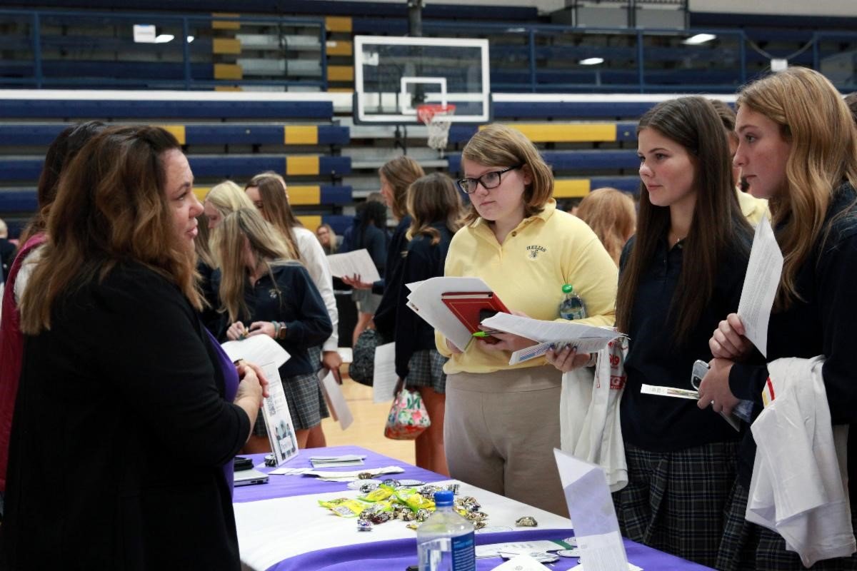 Lori Stoll, Food Programs Coordinator for Catholic Charities of Central and Northern Missouri, and Chelle Smith-Vandergriff, senior director of Volunteer Engagement, visit with students at Helias Catholic High School in Jefferson City during a service fair in October 2022.